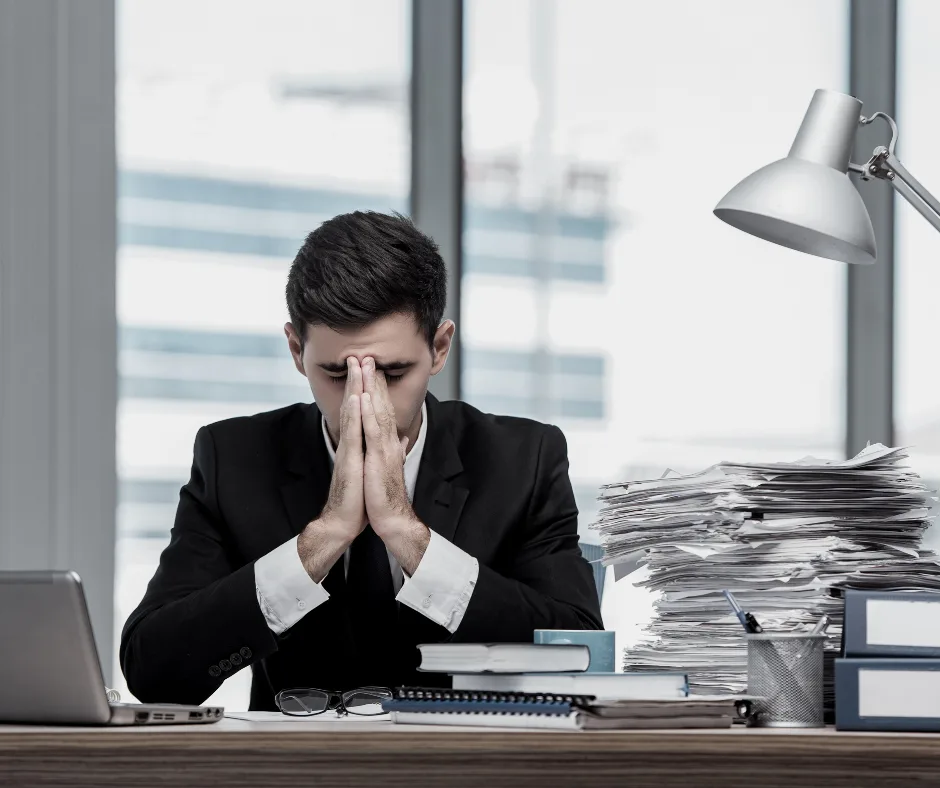 Stresszes vállalkozó a felgyűlt iratok és számlák mögött